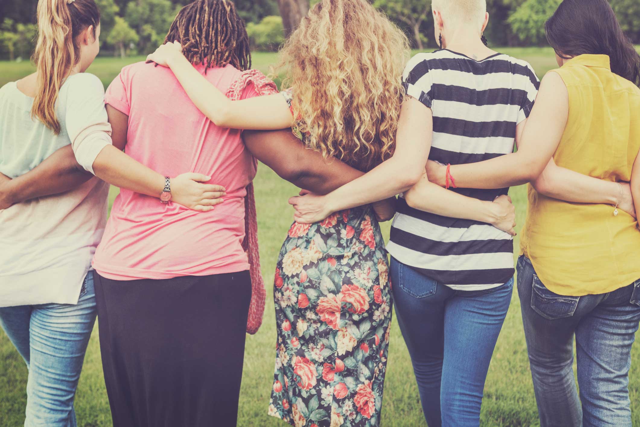 5 women standing with their backs to us linking arms