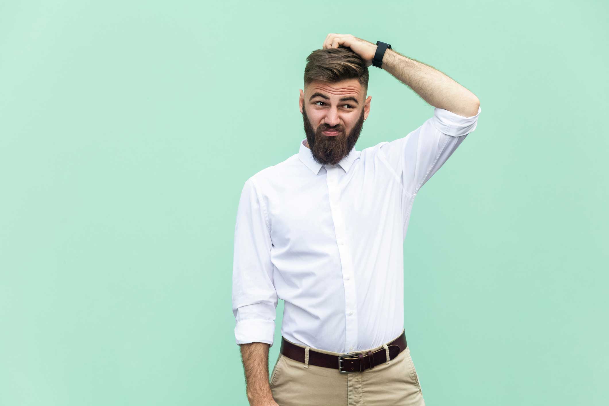 A man with a beard scratching his head