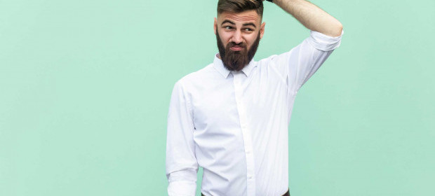 A man with a beard scratching his head