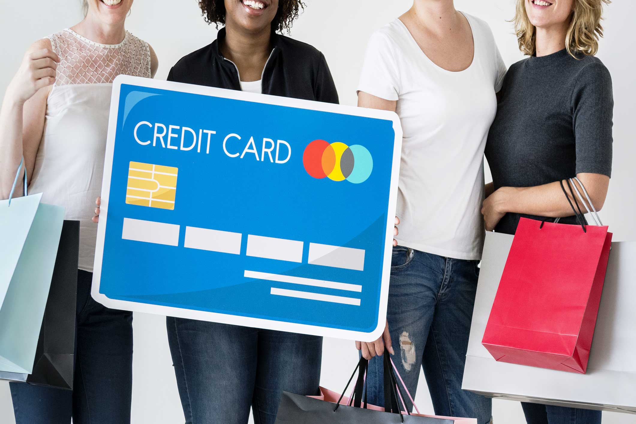 A group of 4 women standing together with shopping bag with a credit card graphic in front of them 